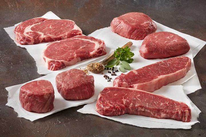 Raw beef steaks on a dark surface with paper underneath