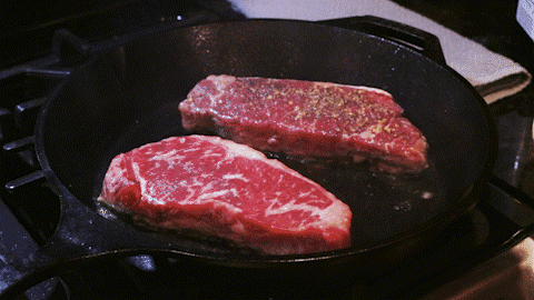 pan frying steaks on iron skillet