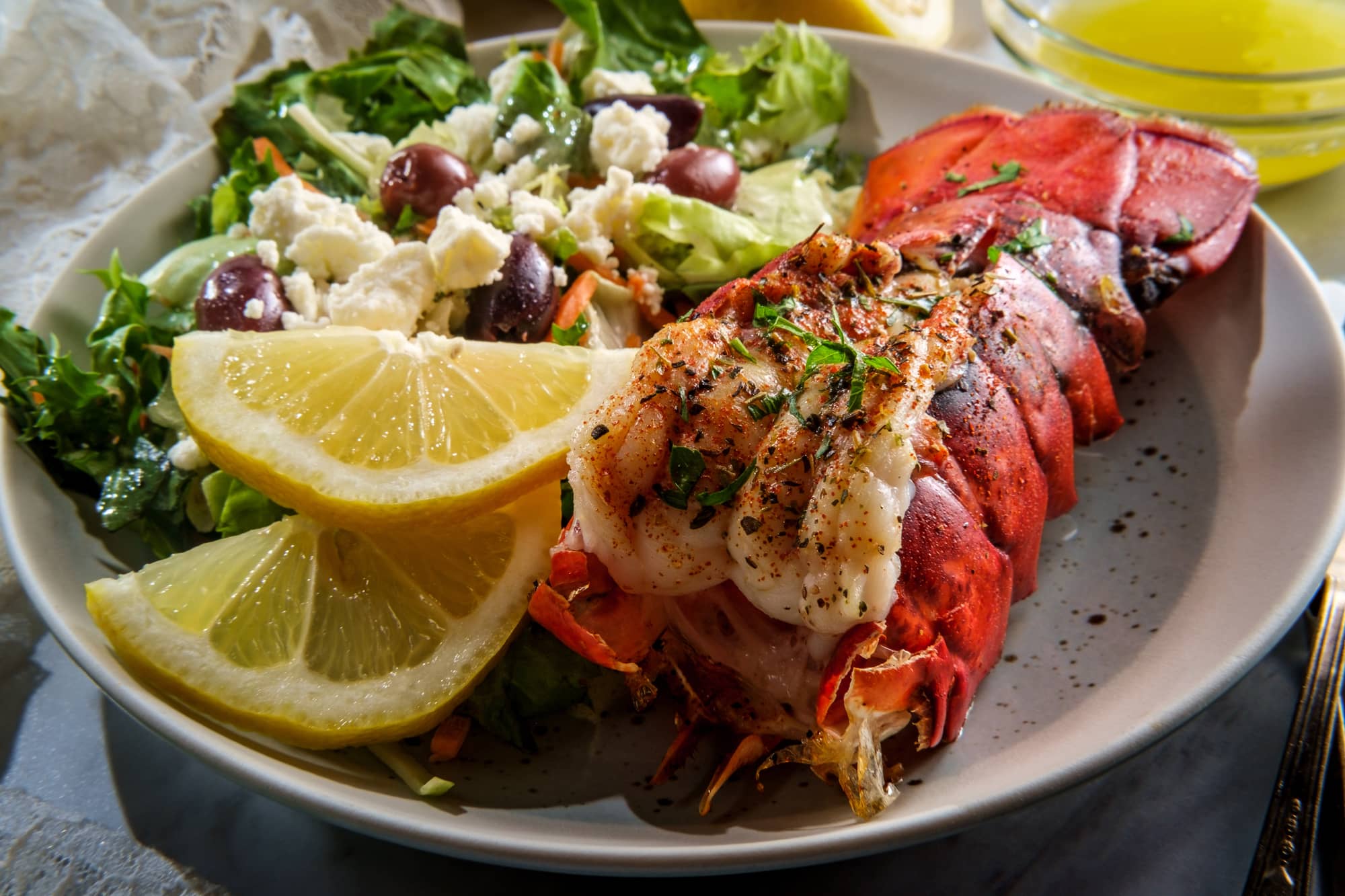 lobster tail served with greek salad and lemon slices