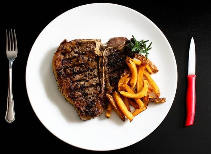 porterhouse steak on plate with french fries