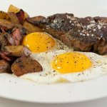 t-bone steak and eggs with potatoes on a platter