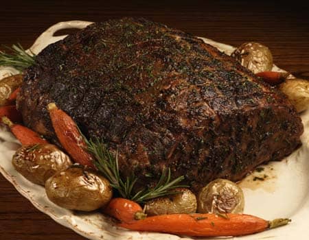 cooked prime rib with rub and served with carrots and potatoes