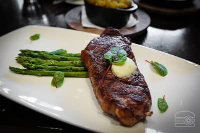 new york strip steak cooked and served on platter with asparagus
