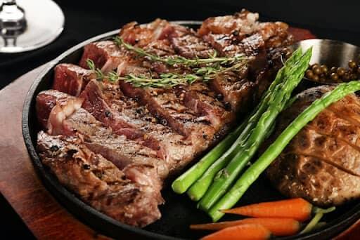 tri tip and ribeye steak served with asparagus and carrots