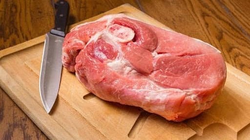 pork shoulder steak on cutting board with knife